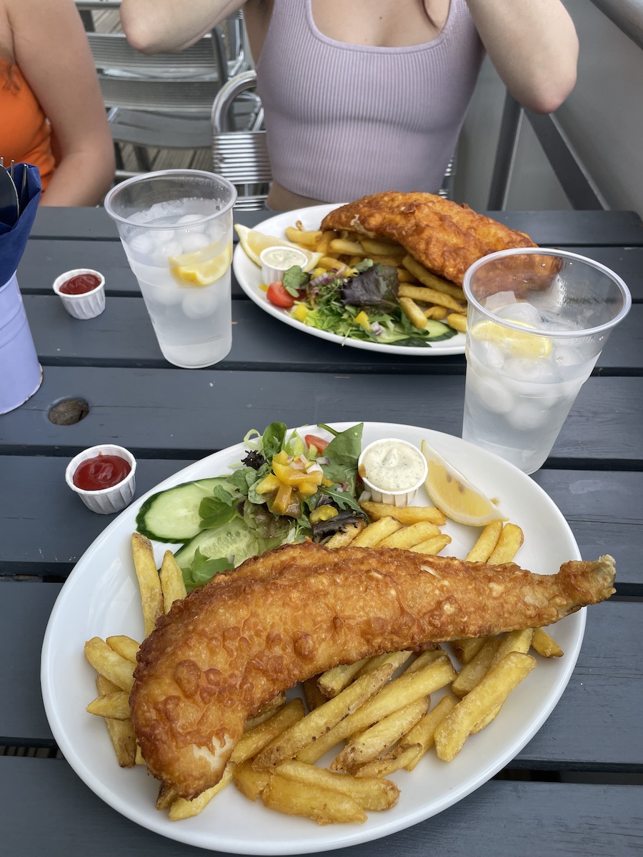 Two dishes of Fish & Chips with water and salad