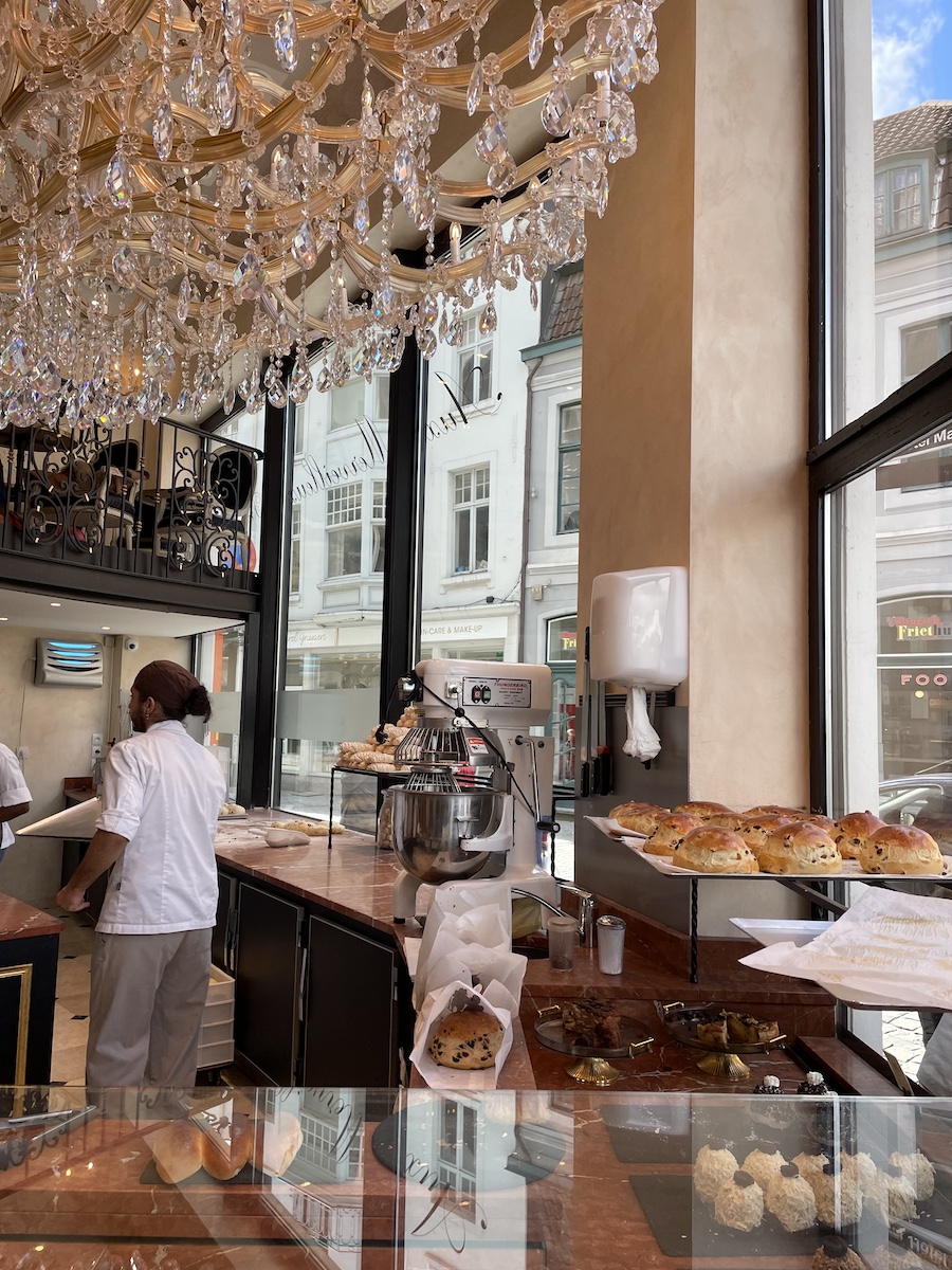 Chandalier over pastries behind glass in cafe