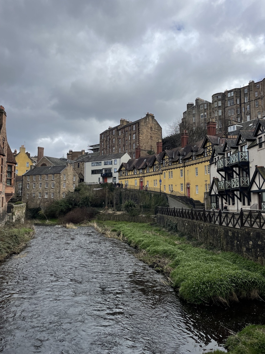 River with sidewalk curving around with white and yellow buildings