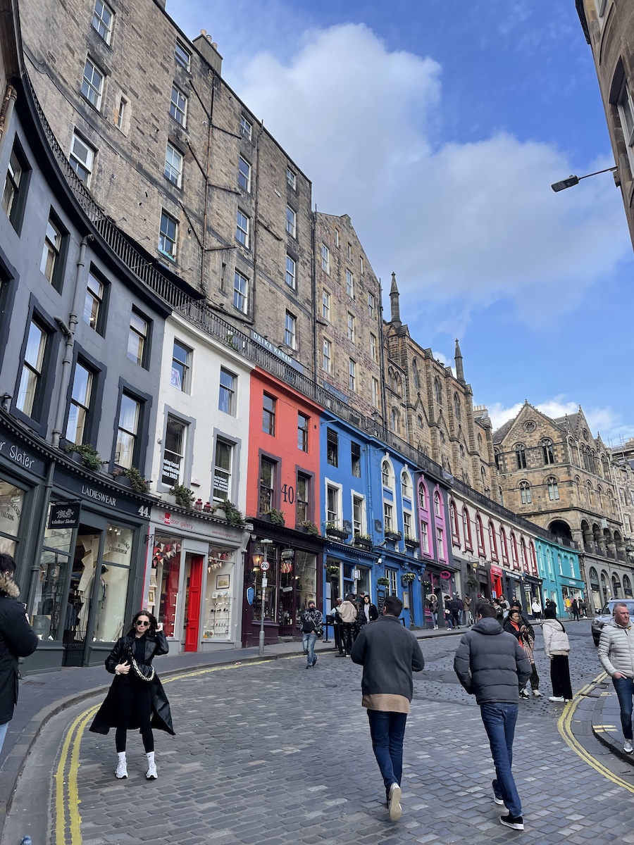 Colorful stores on curved uphill road with brown buildings above