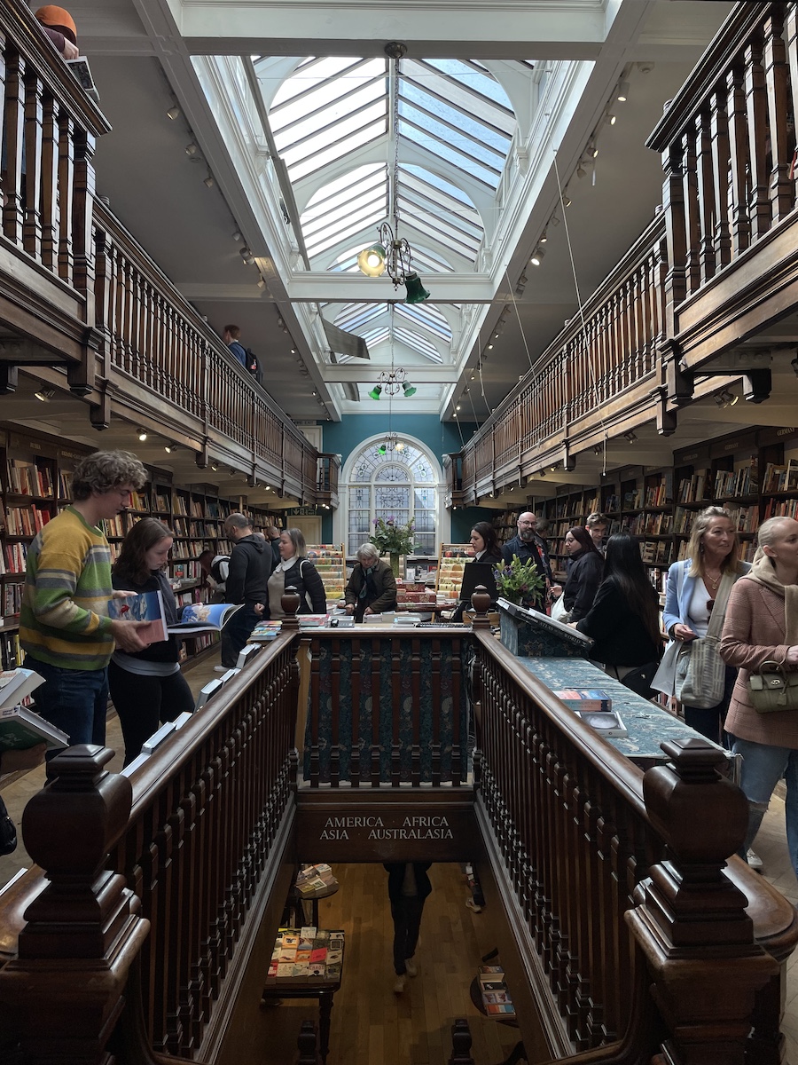 Symmetrical indoor of book store, with individuals holding and reading books