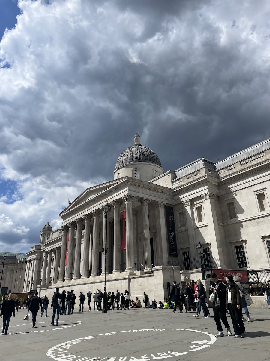 Side view of entrance of white building with pillars and large red banners