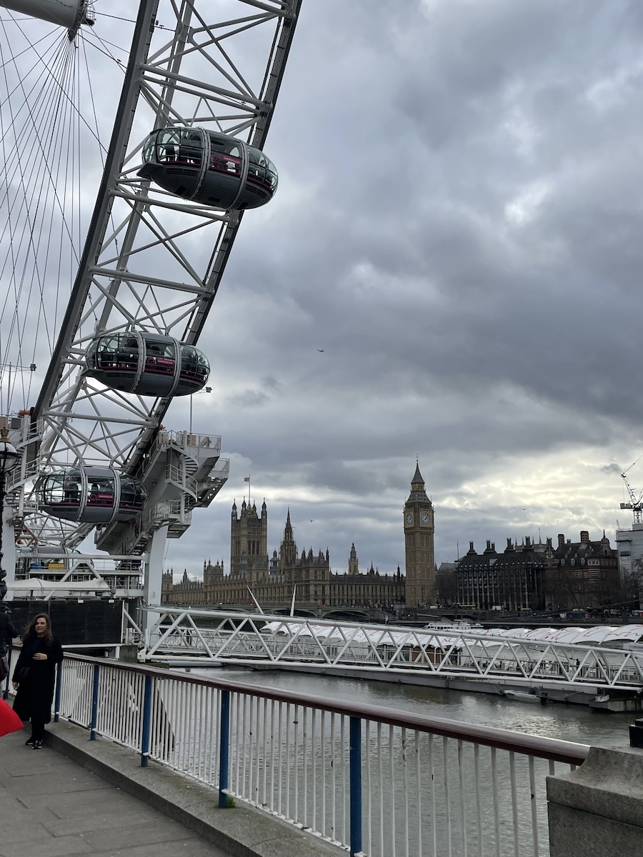 Edge of London Eye ferris wheel with Big Ben small in background across river
