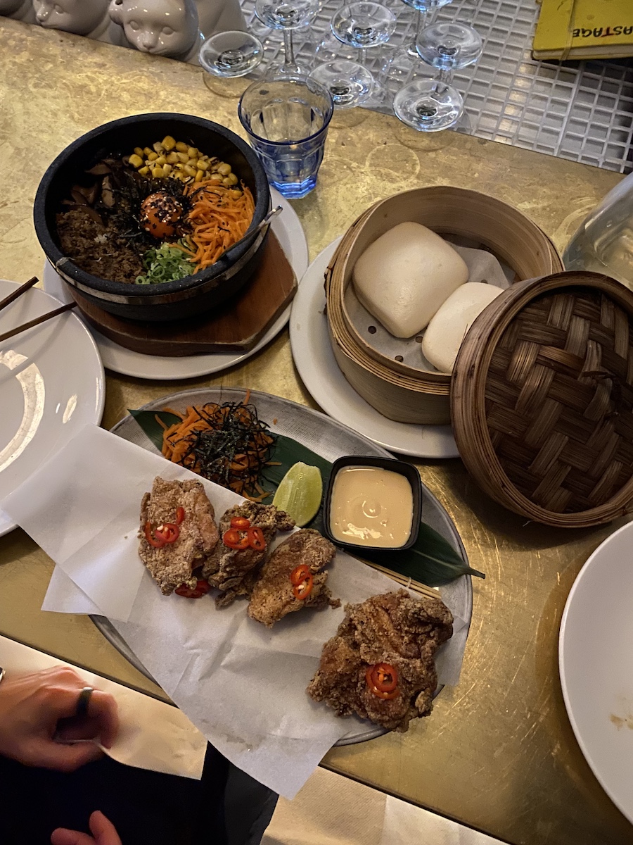 One dish with bimbimbap, one dish with 4 pieces of fried chicken, and 2 buns in steam container