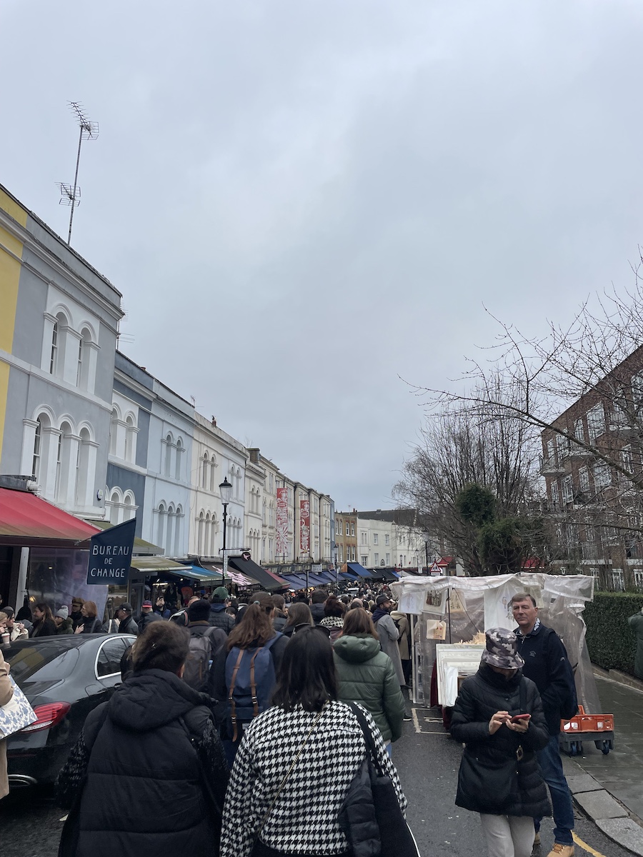 Crowd walking down a slightly curved street and buildings with open stalls