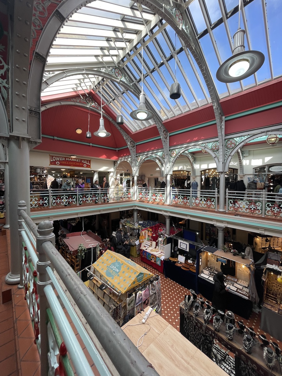 Side view of indoor market stalls under clear roof taken from second floor