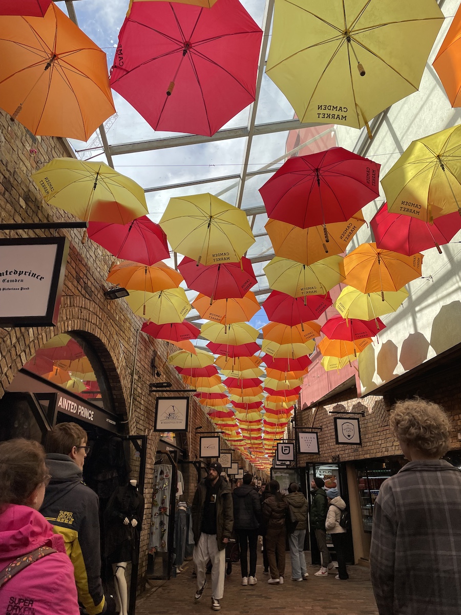 Rows of orange, red, and yellow umbrellas hung with 'Camden Market' written