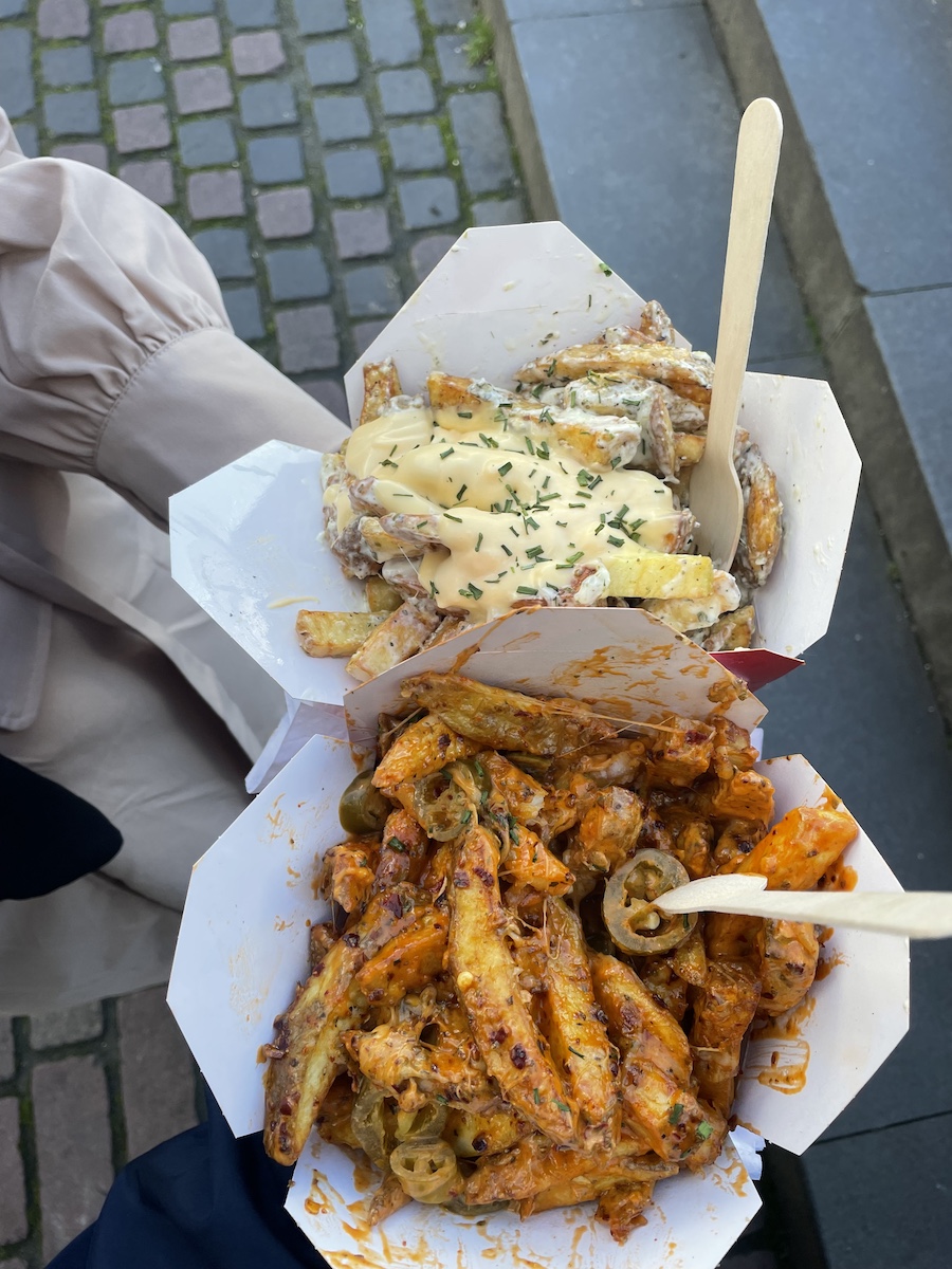 Two chinese boxes loaded with fries, one spicy, one cheesy