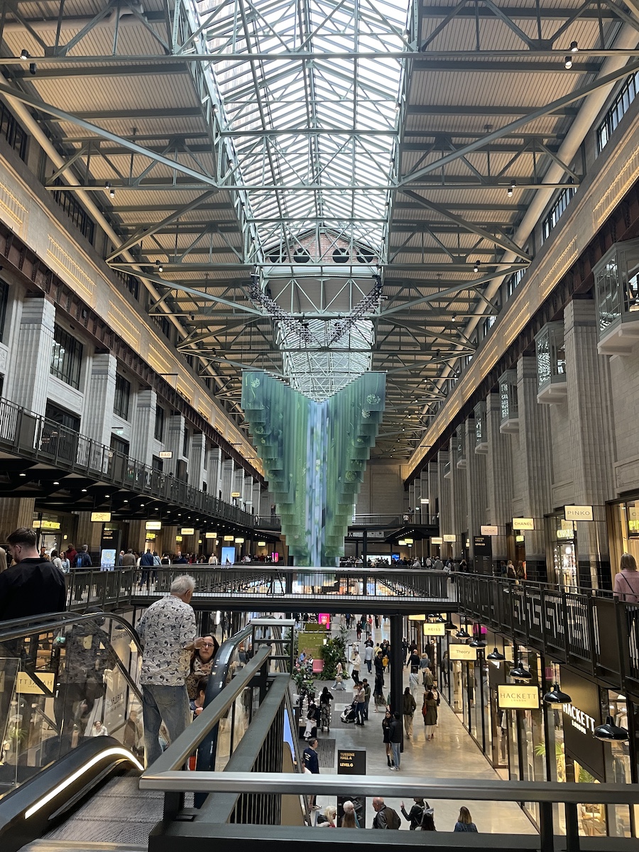 Symmetrical indoor of shopping mall from second floor, two hallways with rows connecting across