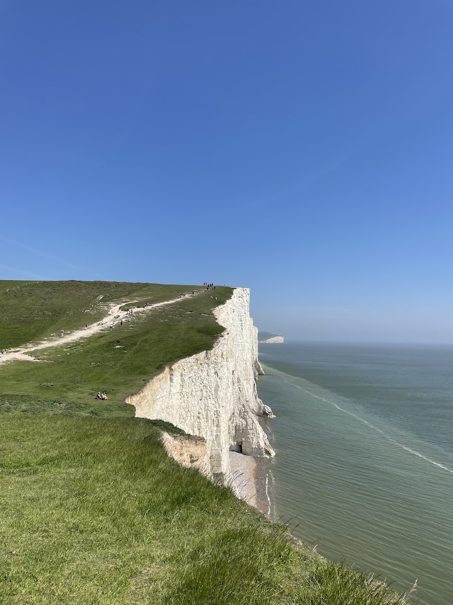 Side view of white cliff wall and grass top, with water below