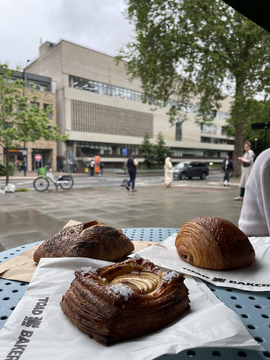 Three pastries on bag on blue table in front of school background
